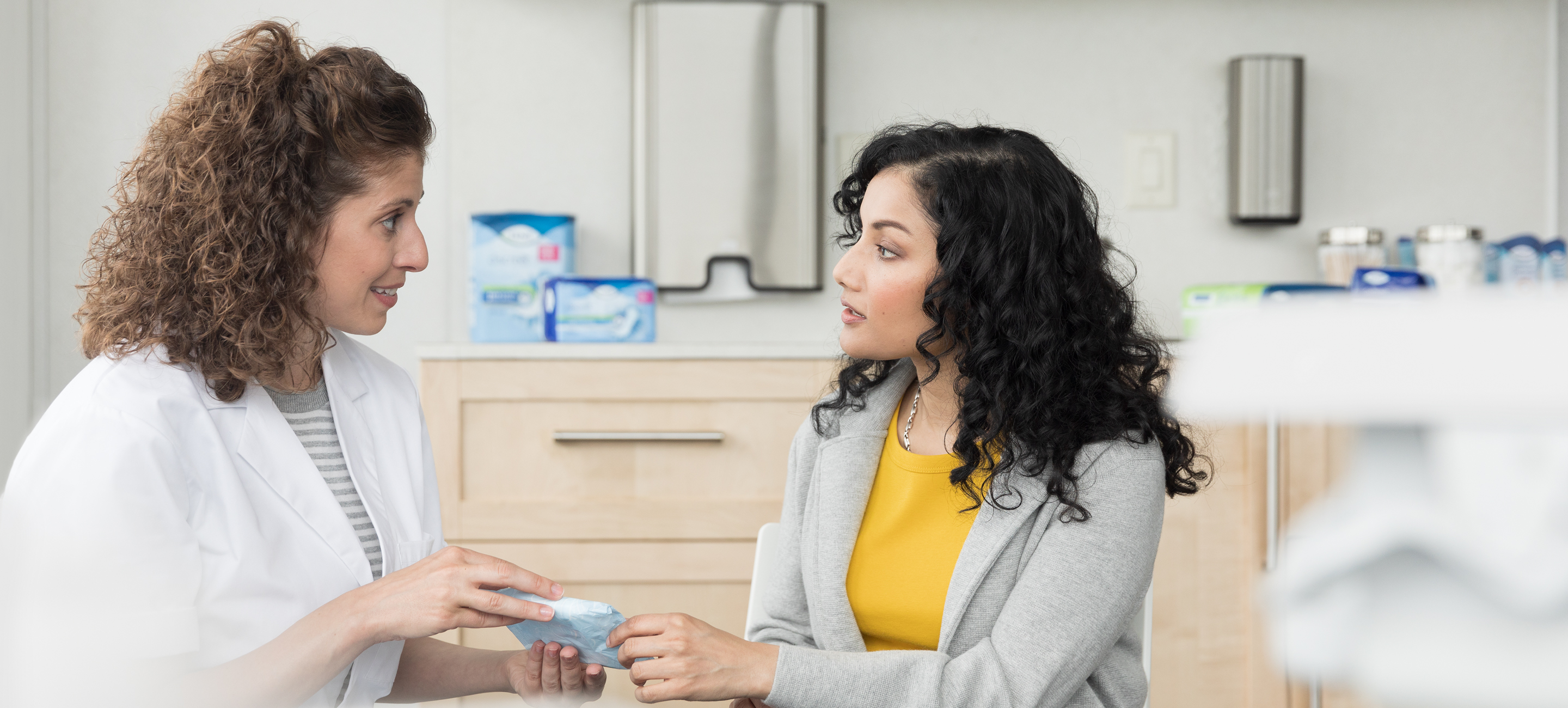 Female doctor talking to female patient holding TENA pad Female doctor talking to female patient holding TENA pad